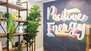 Una habitación con un amplio mural que dice "Positive Energy", estantes con plantas y suelo de madera.