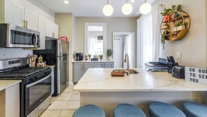 Una cocina moderna con electrodomésticos de acero inoxidable, una isla central y taburetes de bar azules.