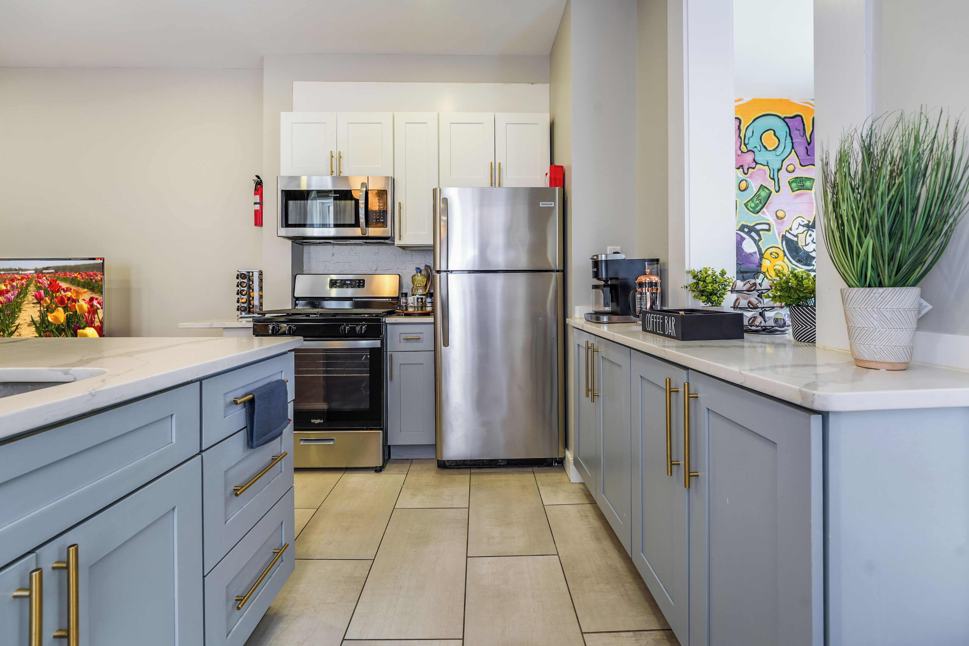 A modern kitchen with stainless steel appliances, white cabinets, and a tiled floor.