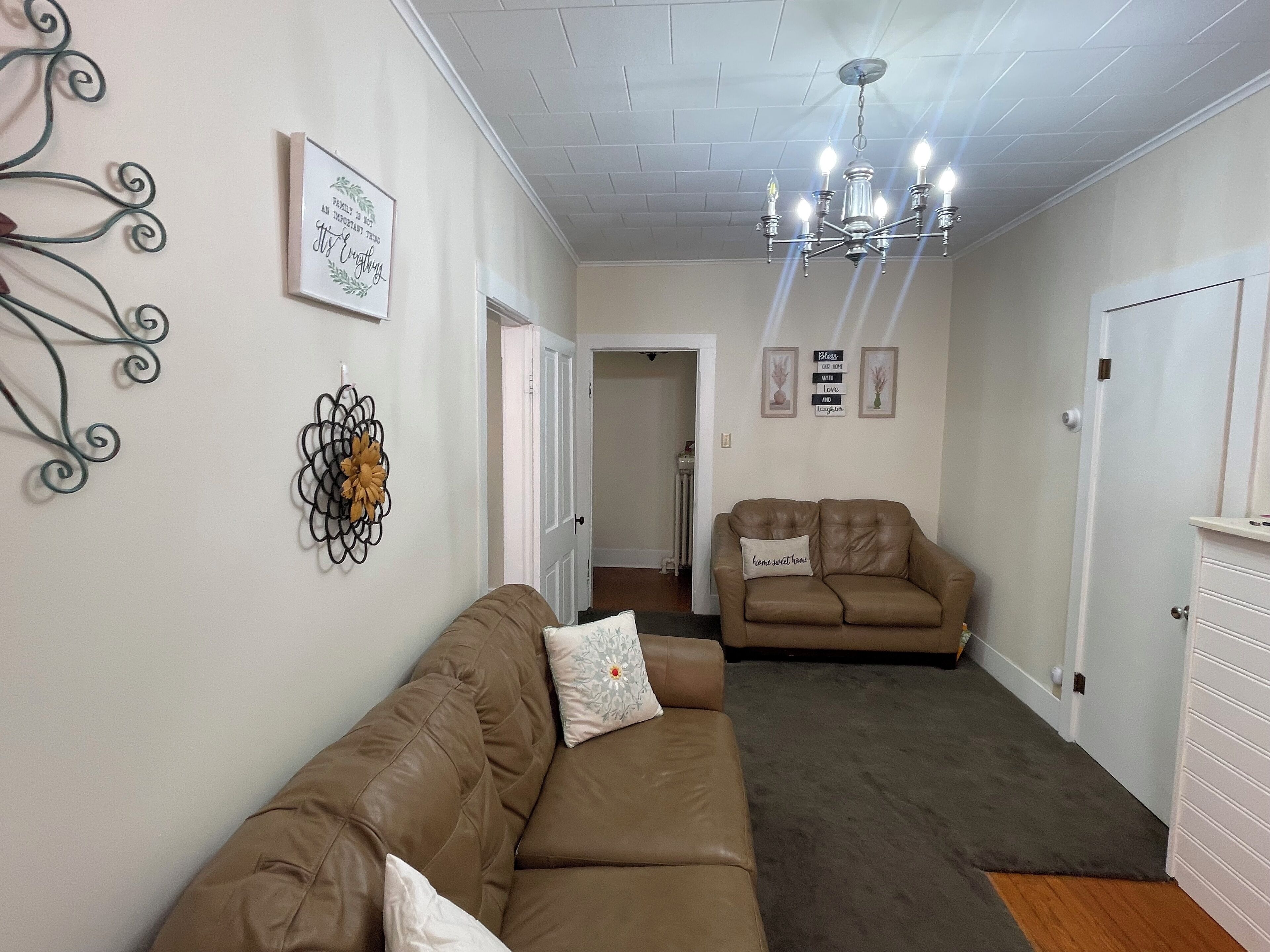 A living room with two sofas, a chandelier, and wall decorations.