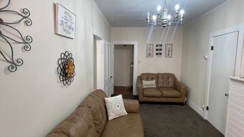 A living room with two sofas, a chandelier, and wall decorations.