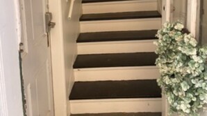 Un pasillo estrecho con una escalera que sube.
