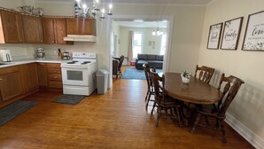 Una cocina con armarios de madera, una estufa blanca y un comedor con mesa y sillas de madera.