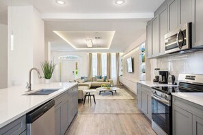 A modern kitchen with a dishwasher, stove, and a dining area with a sofa and coffee table. - Mario, Mickey & Jedi Arcade Villa w/ Themed Rooms (Kissimmee)