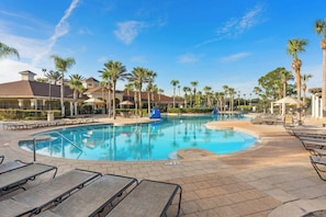 A swimming pool with lounge chairs and palm trees.