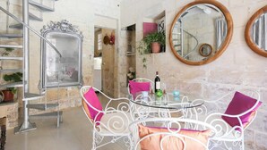 Ein Zimmer mit Wendeltreppe, runden Spiegeln, einem Tisch mit Stühlen und einem Topfpflanzen.