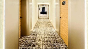 Un pasillo de hotel con alfombra estampada, puertas de madera y un cartel que indica los números de habitación 109-110 y 111-112.