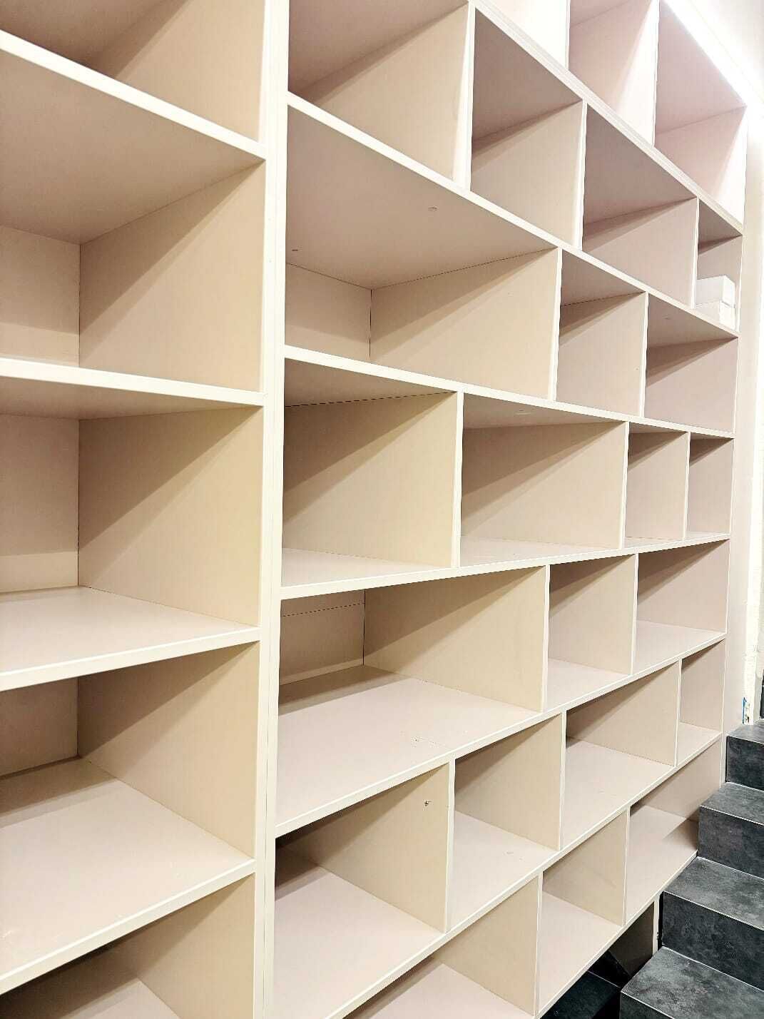 Conjunto de estanterías color beige, vacías, con una escalera que baja.