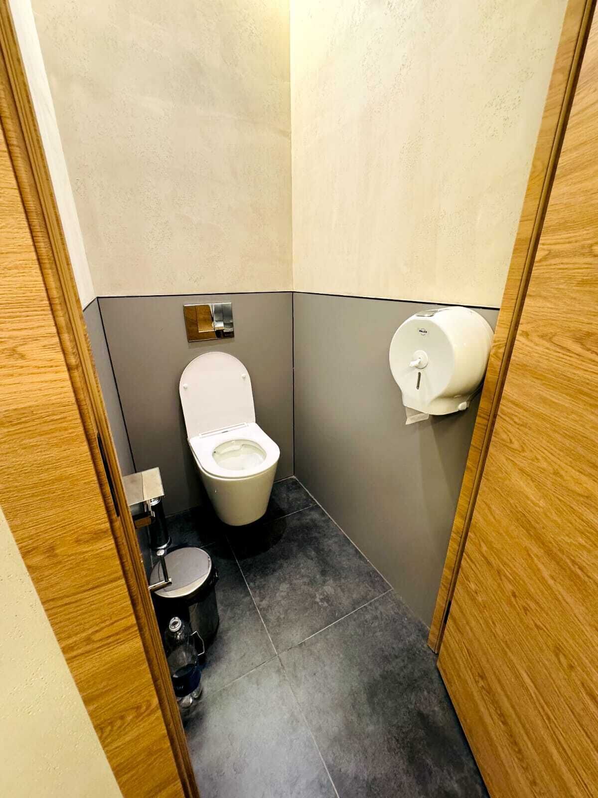 A small, compact bathroom with a toilet, bidet, and hand dryer.