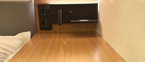 A compact kitchenette with a wooden countertop, two electrical outlets, a USB port, and a small shelf.