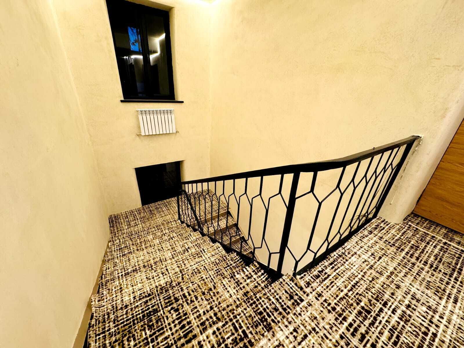 A staircase with a patterned carpet and a metal railing.