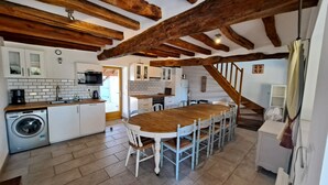 Una cocina con una mesa y sillas de madera, una lavadora y una escalera.
