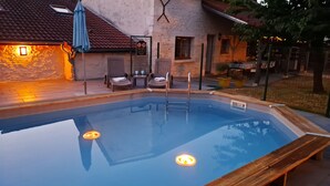Una piscina con muelle de madera, sillas de descanso y un letrero de seguridad.