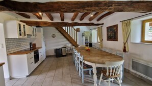 Una cocina con armarios blancos, una mesa de madera y una escalera que lleva a otra habitación.