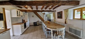 Una cucina con mobili bianchi, un tavolo in legno e una scala che conduce in un'altra stanza.