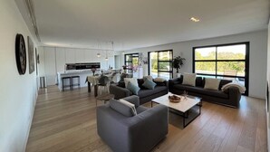 A spacious living area with a sofa set, a coffee table, and a kitchen in the background. - Modern villa, fast WiFi, A/C, pool in private backyard, ideal for fun and work (Vallauris)