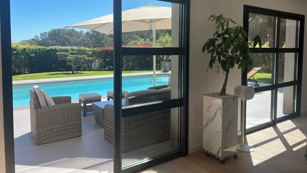 A modern room with large sliding glass doors leading to a pool area. - Modern villa, fast WiFi, A/C, pool in private backyard, ideal for fun and work (Vallauris)