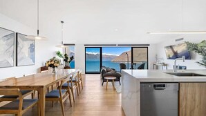 A modern kitchen with a wooden dining table, chairs, and a built-in dishwasher.