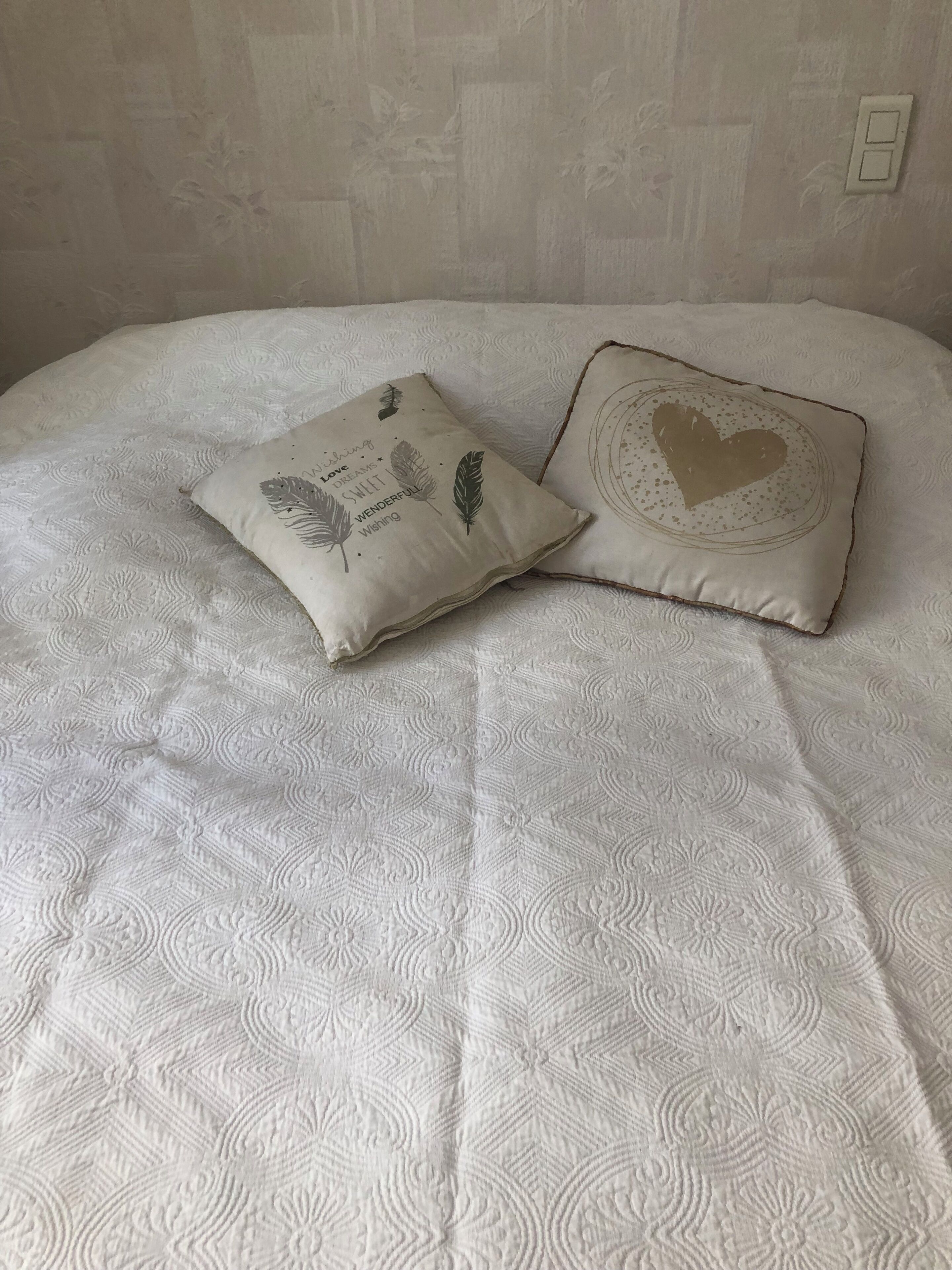Ein Bett mit weißer, strukturierter Bettdecke und zwei Zierkissen.
