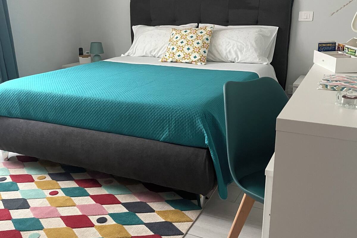 Une chambre à coucher moderne avec un lit, un bureau et un tapis coloré.