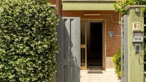 A gated entrance with a wooden door, a brick building, and a green wall with a mailbox. - B&B MARGIÒ  (Fiumicino)