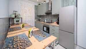 A compact kitchen with a wooden table, a built-in oven, and a stainless steel refrigerator. - B&B MARGIÒ  (Fiumicino)