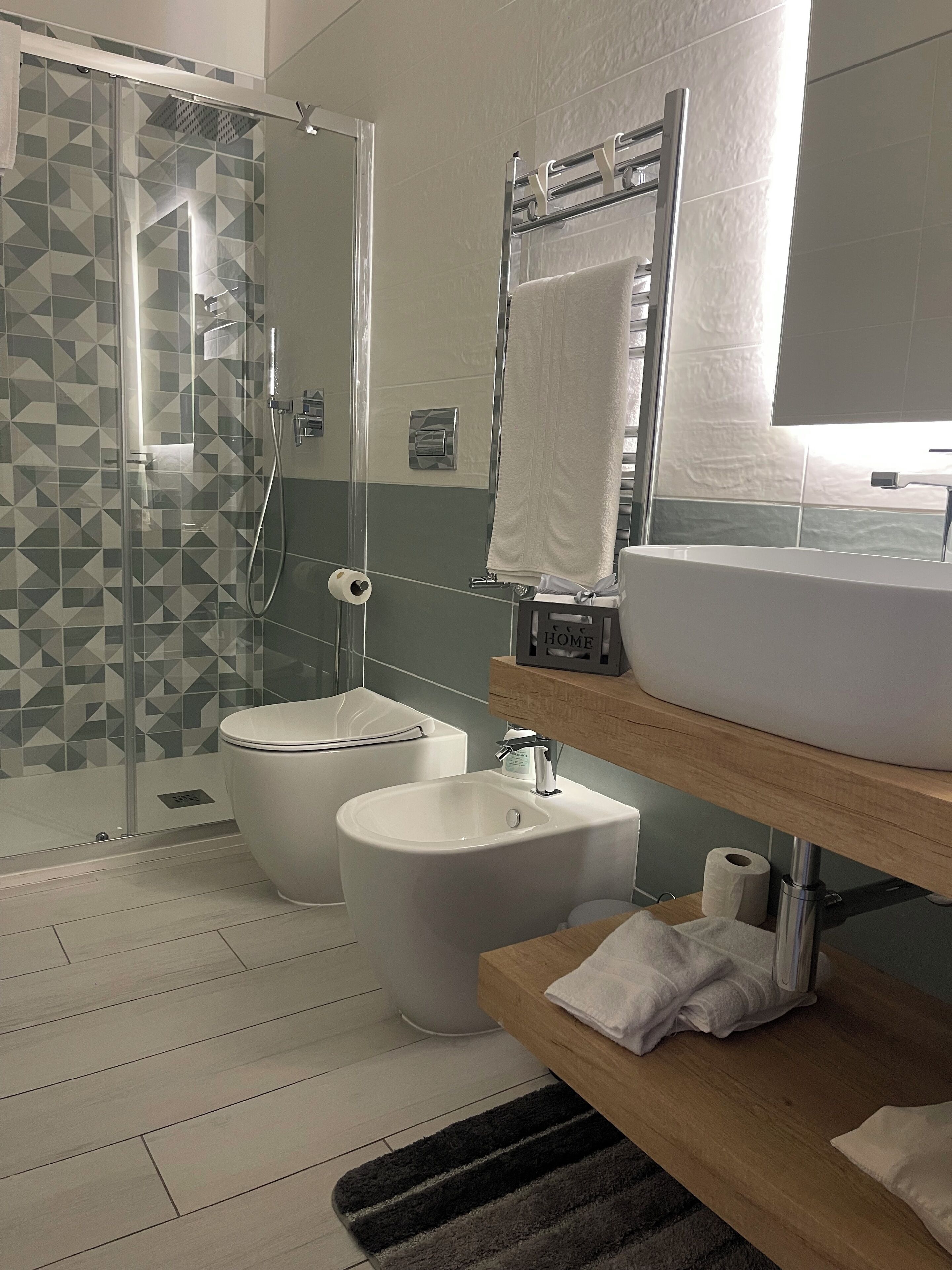 A modern bathroom with a glass-enclosed shower, a white toilet, a sink, and a wooden vanity.