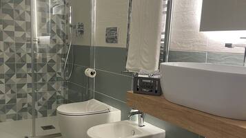 A modern bathroom with a glass-enclosed shower, a white toilet, a sink, and a wooden vanity.