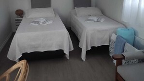A simple room with two beds, a wooden chair, and a sofa. - Monoambiente El Arrayán (Echeverry)