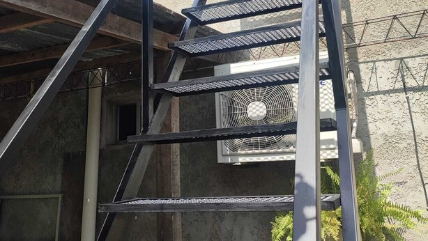 A metal staircase leading to a window, with a building in the background. - Monoambiente El Arrayán (Echeverry)