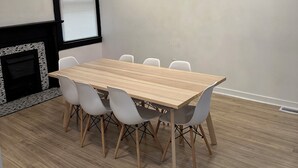 A conference room with a wooden table, white chairs, a black and white tiled fireplace, and recessed ceiling lighting. - Charming 4-bedroom house with WiFi and AC in Pittsburgh (Pittsburgh)
