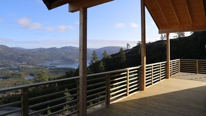 Eine Holzterrasse mit Geländer, die auf eine Berglandschaft mit einem See blickt.