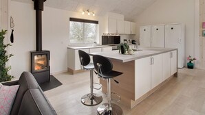 Moderni keittiö, jossa on keskeinen saareke, valkoiset kaapit, sisäänrakennettu liesi ja kattovalokuvio.