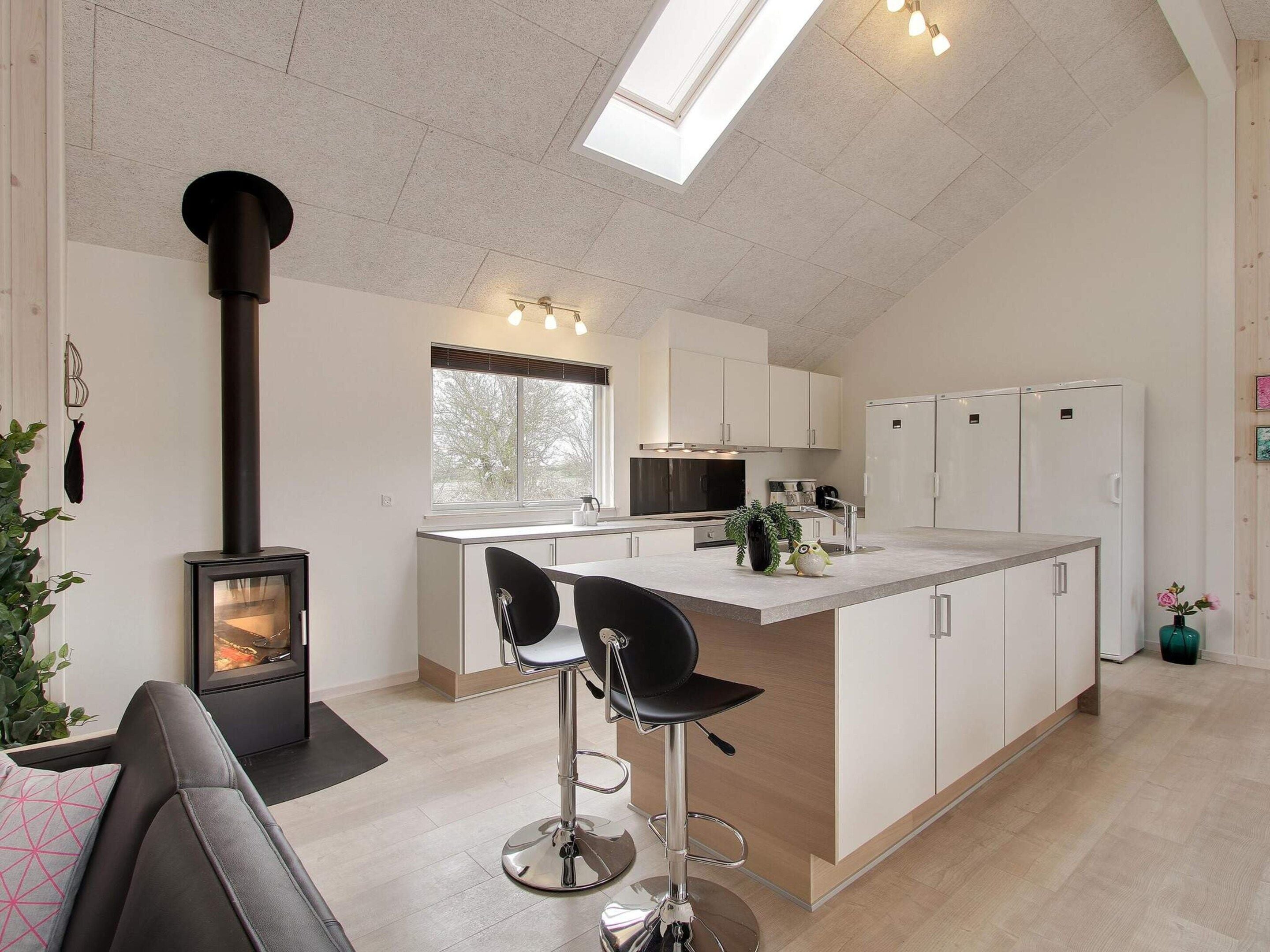 A modern kitchen with a central island, bar stools, a built-in stove, and a skylight.