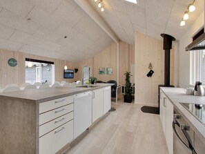 A modern kitchen with a central island, white cabinetry, and a large window. - 5 Star Holiday Home in Bogense (Bogense)
