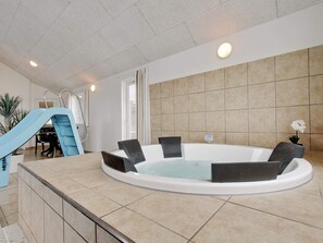 A spa area with a hot tub, a slide, and a seating area.