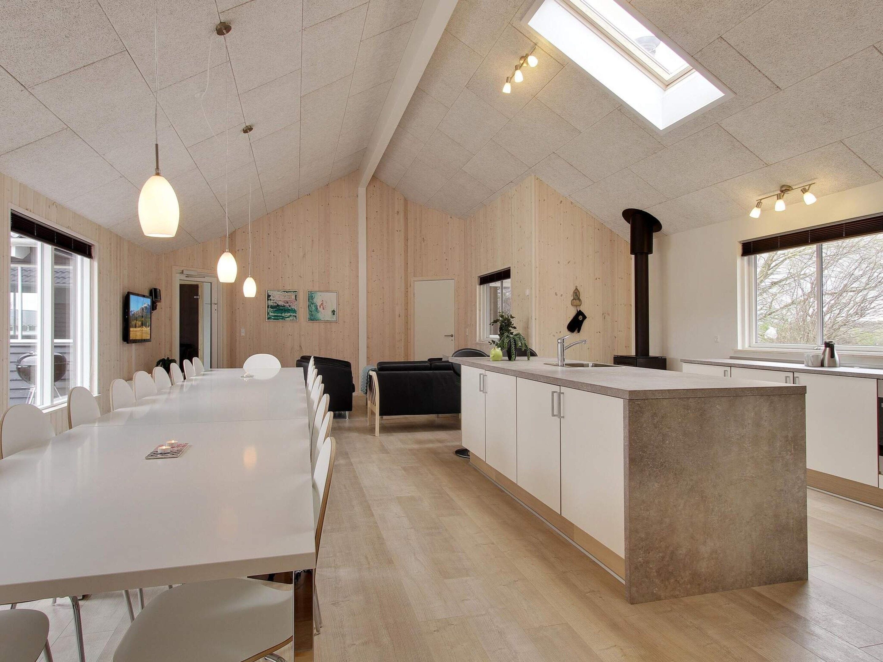 A modern kitchen with a central island, wooden paneling, and a skylight.