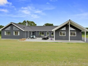 A two-story house with a patio area, a barbecue grill, and a number 38 on the side. - 5 Star Holiday Home in Bogense (Bogense)