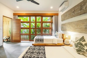 A hotel room with a large window, a ceiling fan, and a bed with a patterned bedspread. - Villa Nya Ubud (Ubud)
