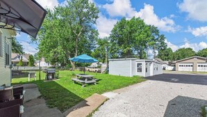 Zona residencial con césped, mesa de picnic y un cobertizo pequeño.