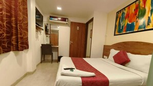 Habitación de hotel con cama, escritorio y televisor.