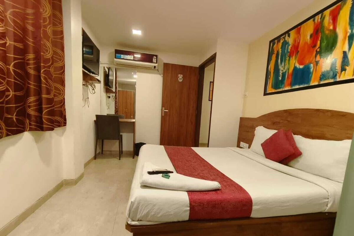 Habitación de hotel con cama, escritorio y televisor.