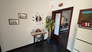 A hallway with a wooden table, framed pictures, a mirror, and a potted plant.