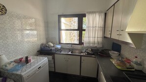 A compact kitchen with a window, a washing machine, and basic amenities.