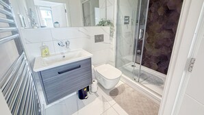 Ein modernes Badezimmer mit einer Duschkabine, einem Waschtisch mit Spiegel und einer Toilette.