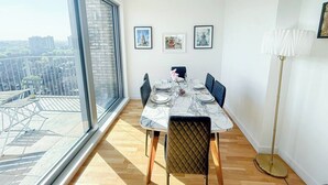 Spiseplads med stort vindue, et bord dækket til fire personer og udsigt over byen.