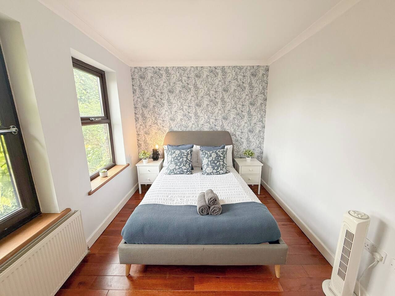 A bedroom with a bed, bedside tables, a window, and a radiator.