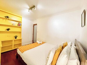 A bedroom with a bed, a yellow dresser, and a door.