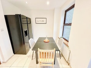 A dining area with a table, chairs, a black refrigerator, and a window with a view.