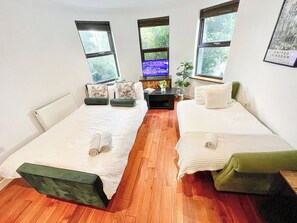 A room with two beds, a small table, and a TV. - New 4-bed Home in Crouch End near alexandra palace (London)